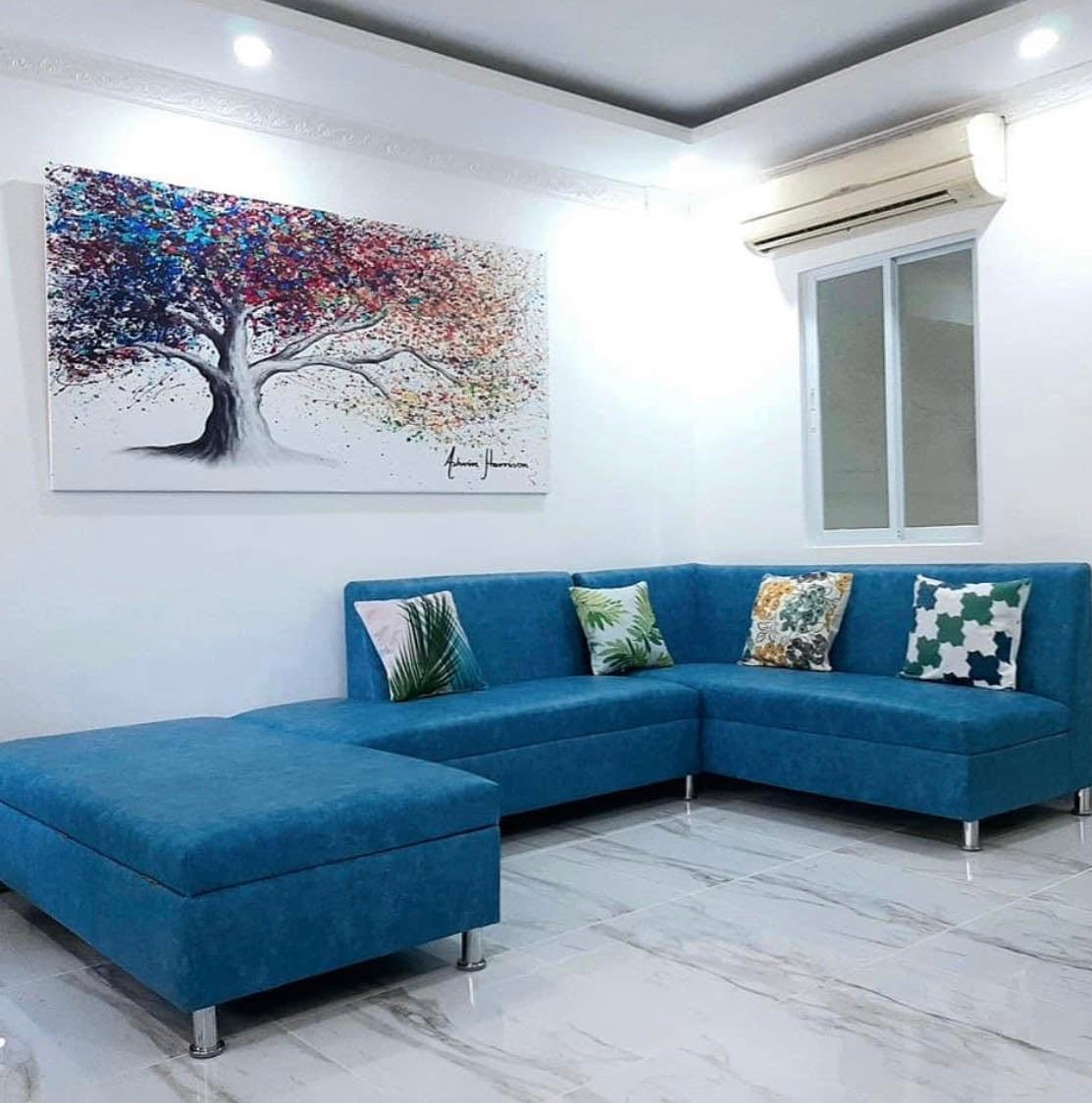 Living room with blue L-shaped sofa and tree artwork